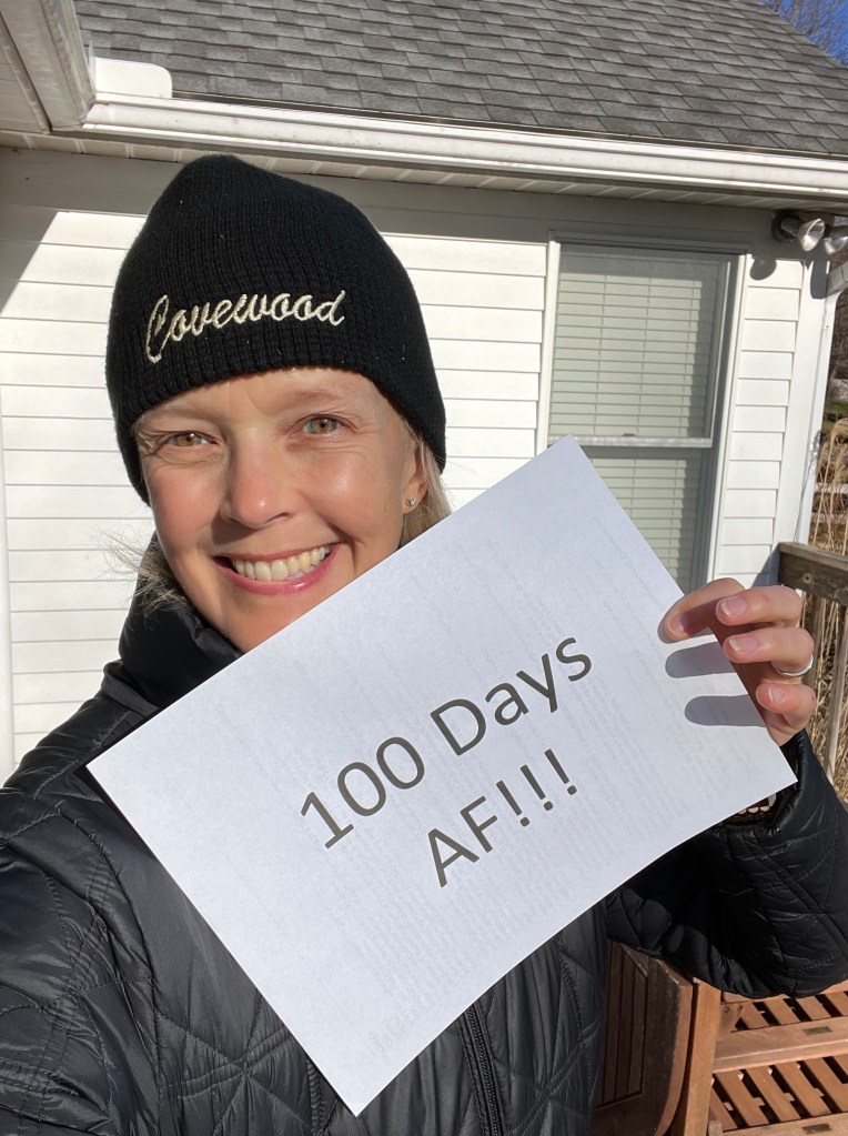 woman holding sign that says 100 Days AF